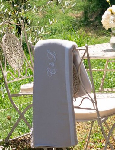 Bannière Serviettes de Plage - L'image montre deux serviettes de plage sur deux chaises autour d'une table sur une pelouse verte, à utiliser pour une journée de détente en plein air.